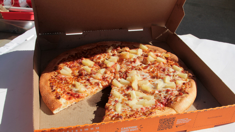 A Little Caesars pizza with a slice missing inside a pizza box.