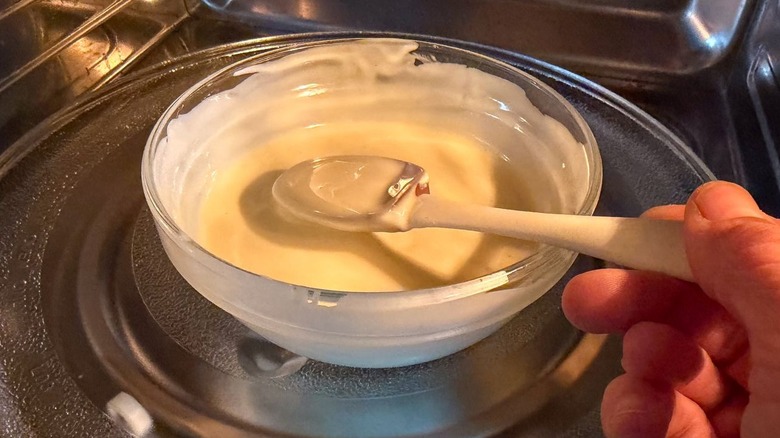 Stirring melted white chocolate in glass bowl in microwave