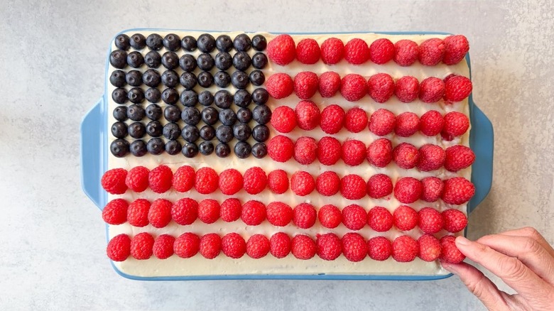 Decorating 13 x 9-inch cake with American flag design with berries
