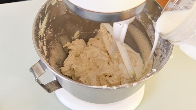 Pouring buttermilk into vanilla cake batter in stand mixer bowl