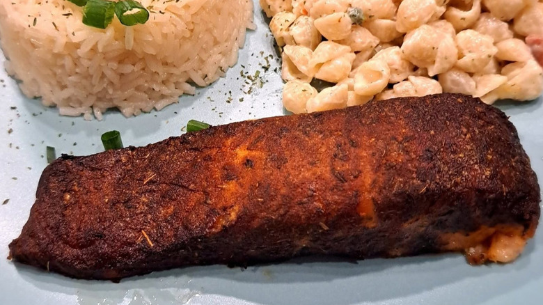 A fillet of Kirkland Signature Atlantic Blackened Salmon next to rice and macaroni salad.