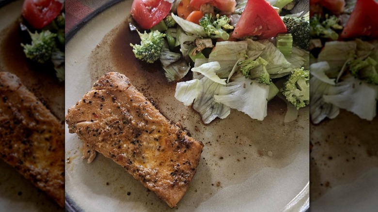 A plate with a slice of Morey's Seasoned Wild Alaskan Salmon next to a salad.