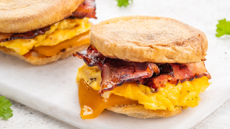 Two bacon, egg, and cheese breakfast sandwiches sit on a white plate