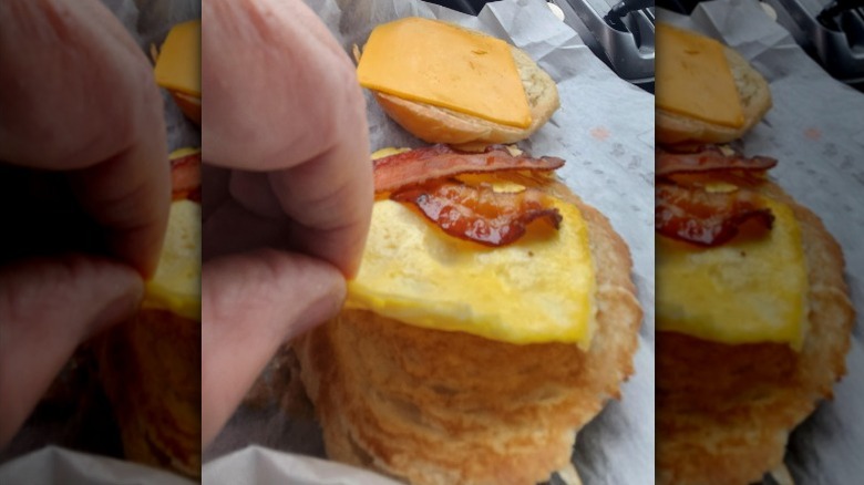 A person shows how small the egg portion of a Burger King Egg and Cheese Biscuit with bacon is