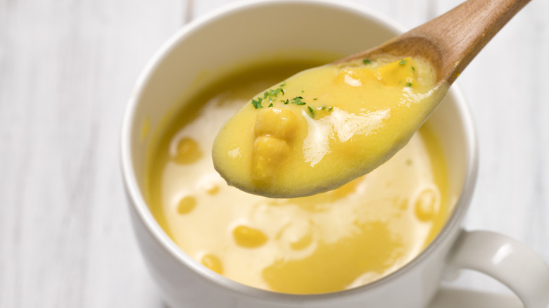 A spoonful and bowl of corn chowder.