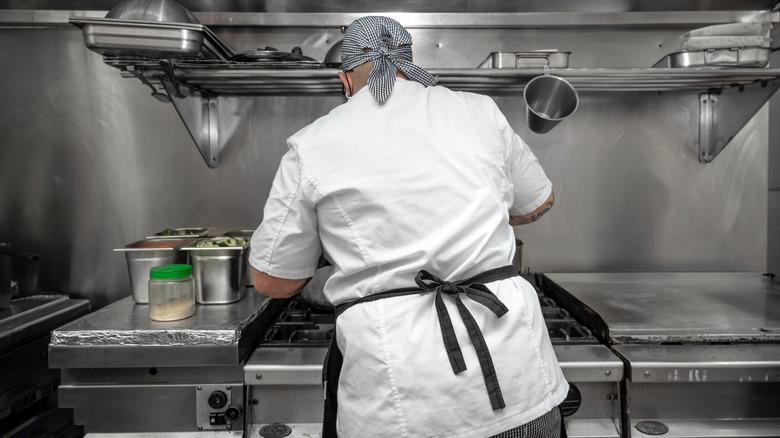 Back of chef cooking food in restaurant