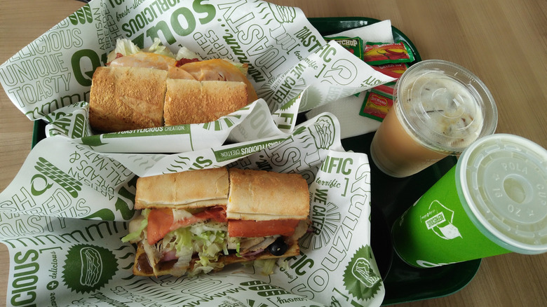 Two Quiznos sandwiches on a tray with beverages