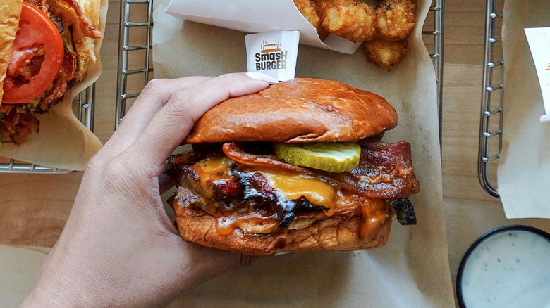 A hand holds a Smashburger