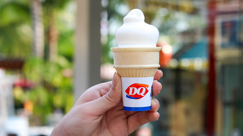 A hand holds a Dairy Queen ice cream cone.
