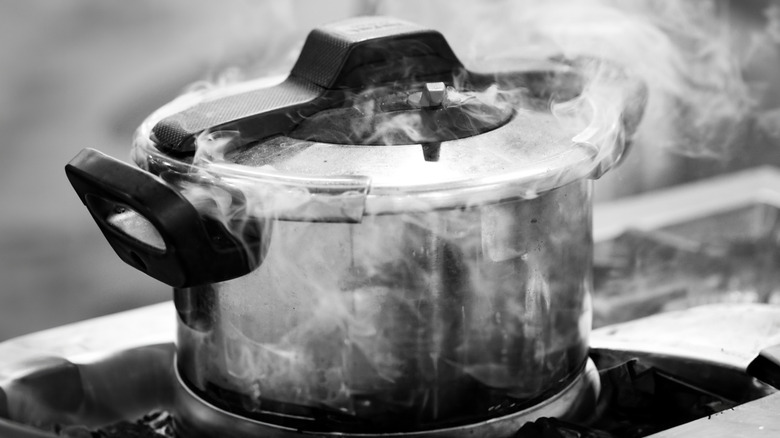 An improperly sealed pressure cooker incorrectly emitting steam from the sides of the lid.