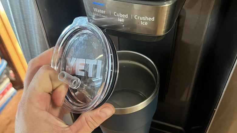 A hand holds a Yeti lid over the water bottle