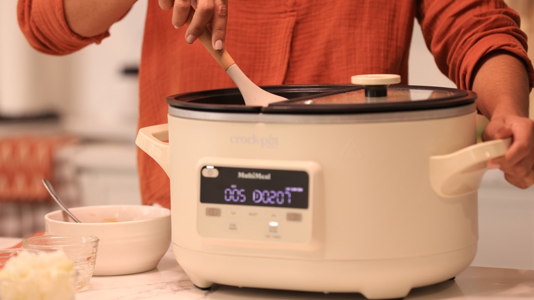 Someone stirs the contents of a Crock-Pot.