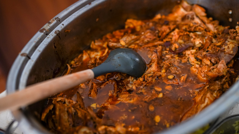 Liquidy shredded meat inside of a Crock-Pot.