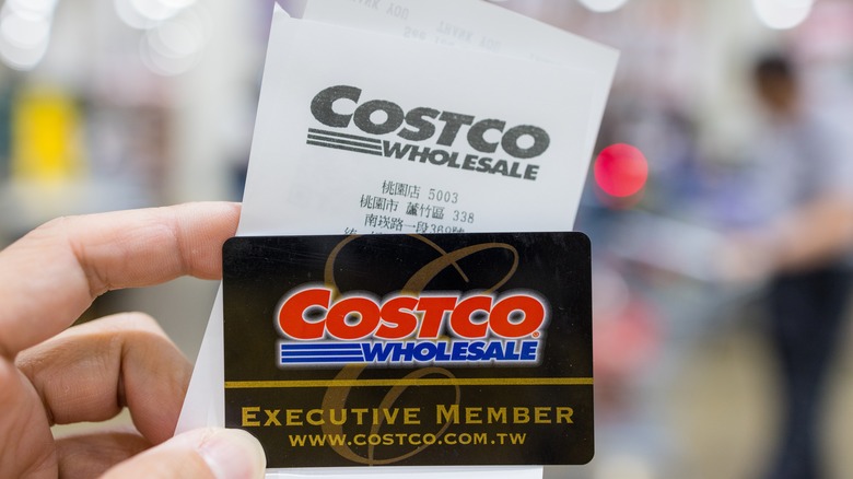 Hand holding a Costco card and receipt