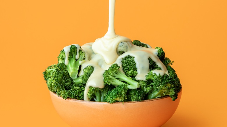 A bowl of broccoli smothered in cheese sauce.