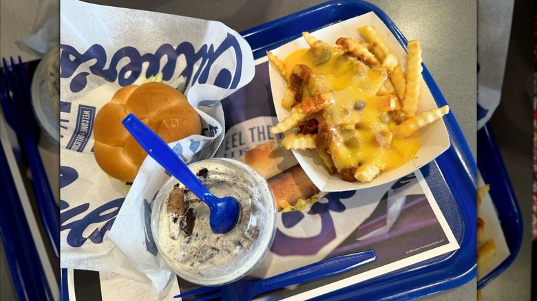 Cheese fries next to a burger and milkshake.