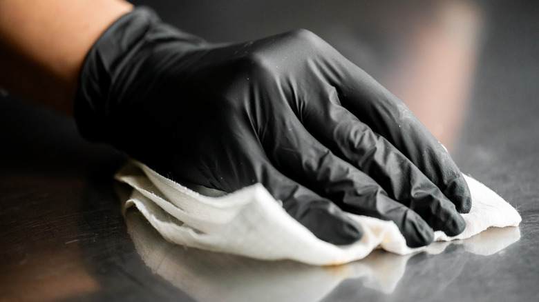 A gloved hand cleans a metal surface