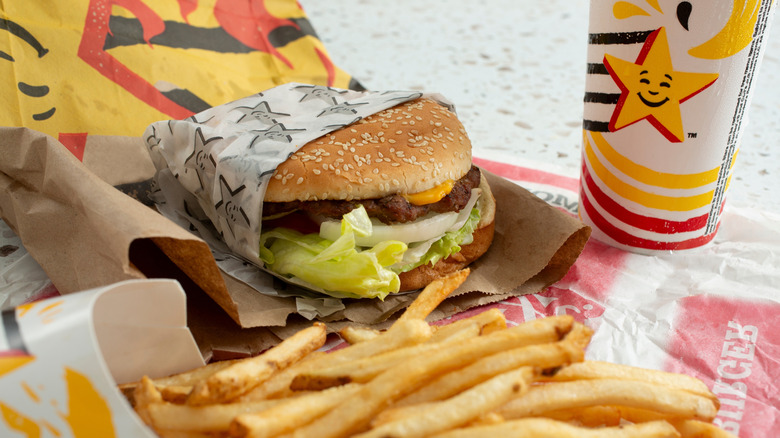 A partially unwrapped Carl's Jr. burger sits near fries and a drink.