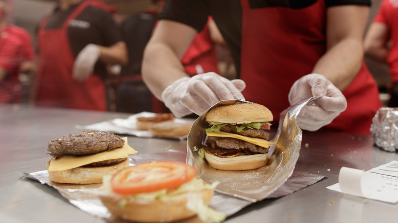 A gloved Five Guys worker wraps a burger in foil