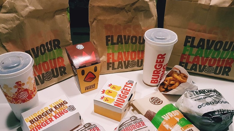 A container of Burger King curly fries next to burgers, drinks, nuggets, and a wrap