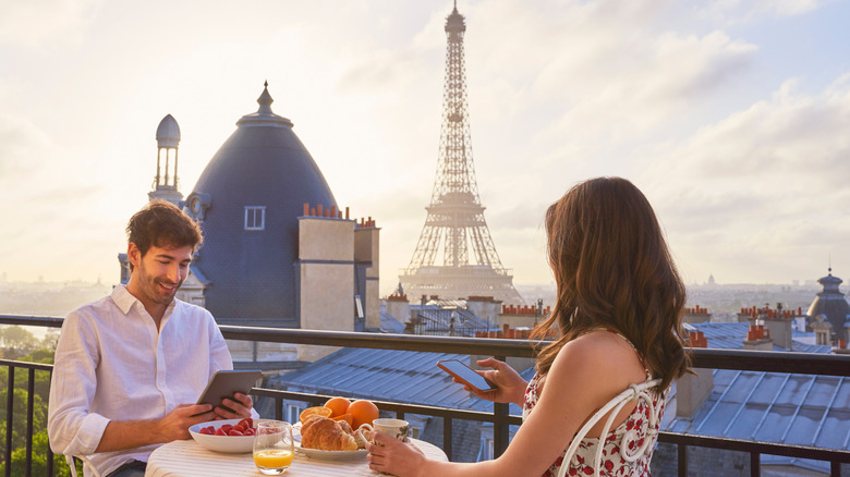 Diners sitting on a balcony overlooking the Eiffel Tower