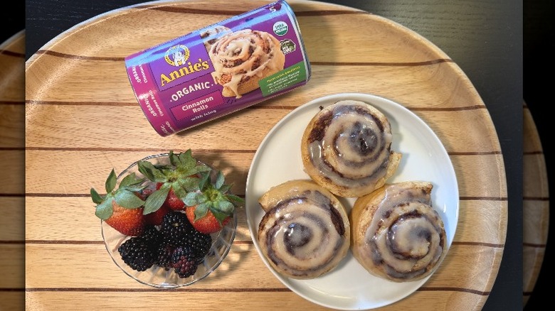 Annie's Cinnamon Rolls on a plate next to their packaging and a bowl of berries