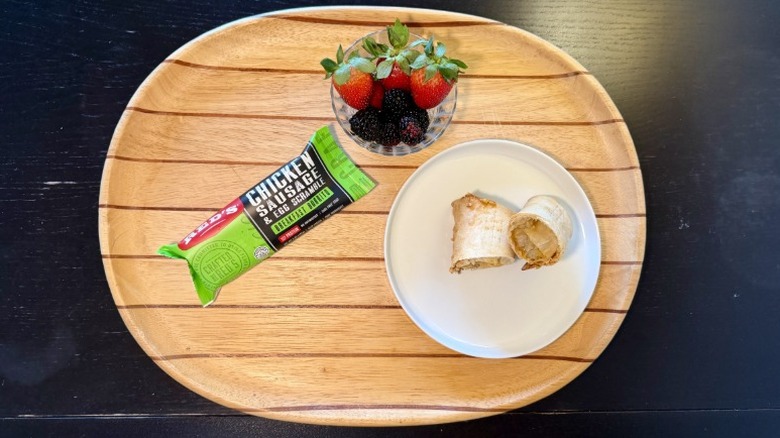 Red's Chicken Sausage & Egg Breakfast Burrito on a plate next to its packaging and a bowl of berries