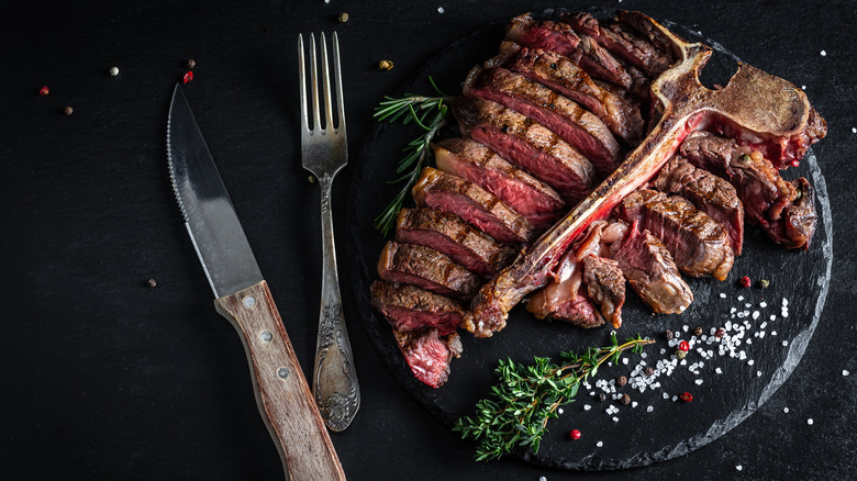 Florentine rib-eye steak on a plate with fresh garnish.