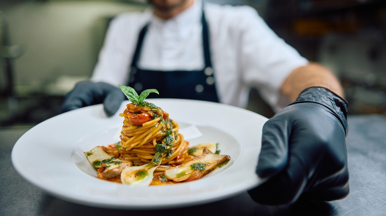 A chef serves pasta in a restaurant.