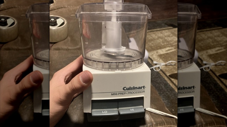 A hand touches a '90s-era Cuisinart food processor.