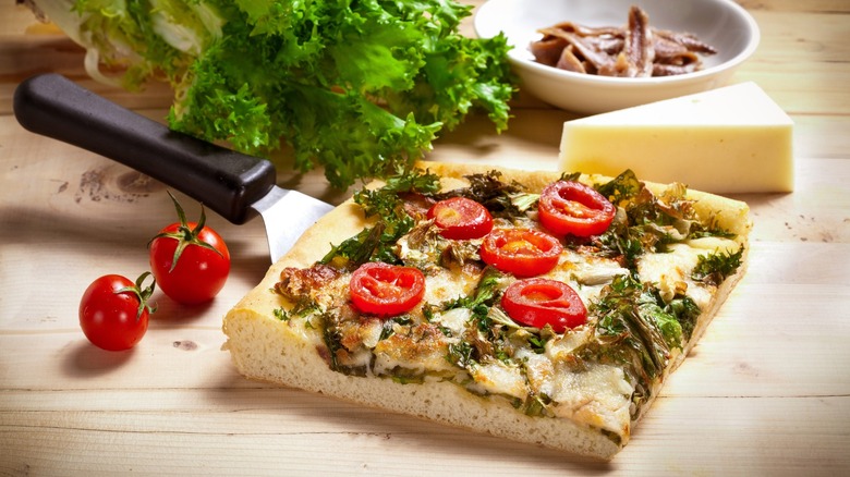 A baked focaccia Messinese slice alongside its toppings.