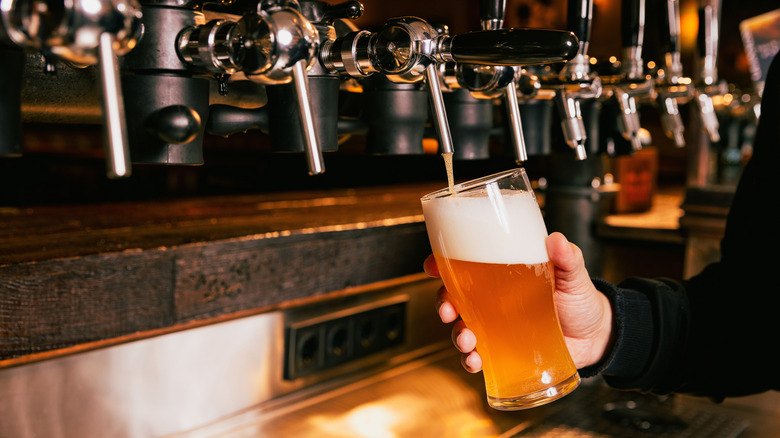Bartender pouring beer into glass.