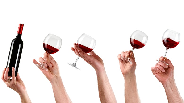 hands holding glasses of red wine