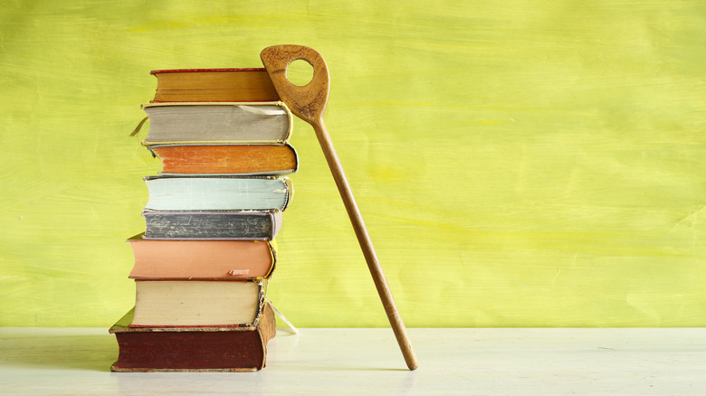 A stack of vintage cookbooks with a wooden spoon leaning against them