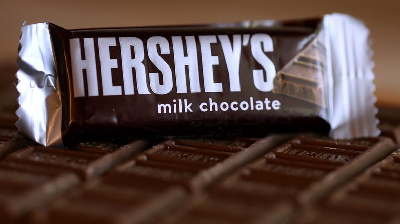 A wrapped Hershey's Milk Chocolate bar sits atop unwrapped bricks of the candy