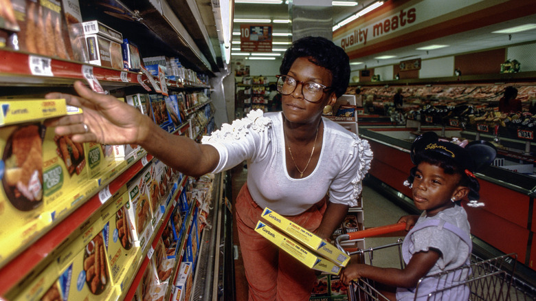 A woman and her daughter shop in a supermarket, circa 1980s