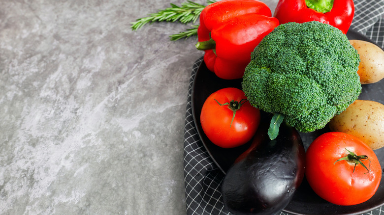 Tomatoes, potatoes, eggplant, peppers, and broccoli on a plate.