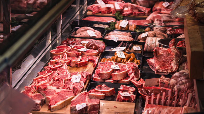 A variety of meats sit in a butcher's display window