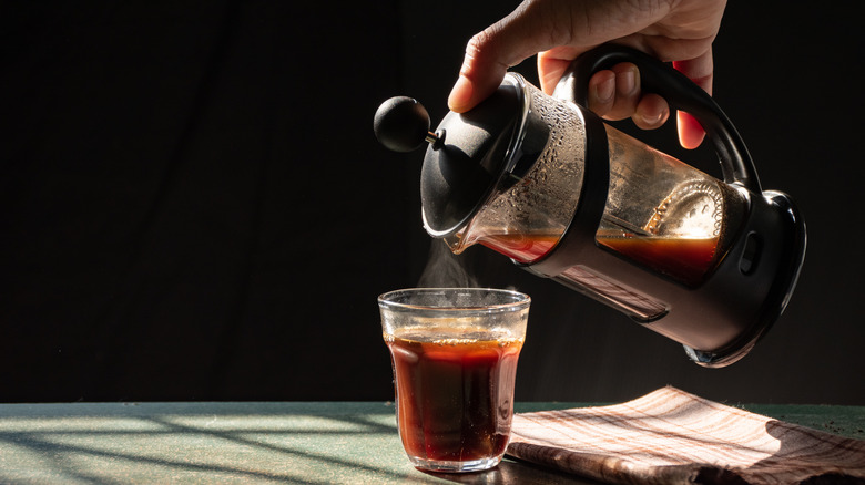 Person pouring French press coffee into a glass