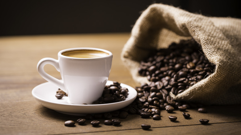 Coffee beans next to a cup of coffee
