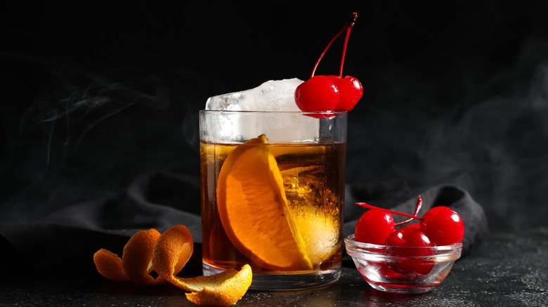 An old fashioned topped with a slice of orange and two cherries.