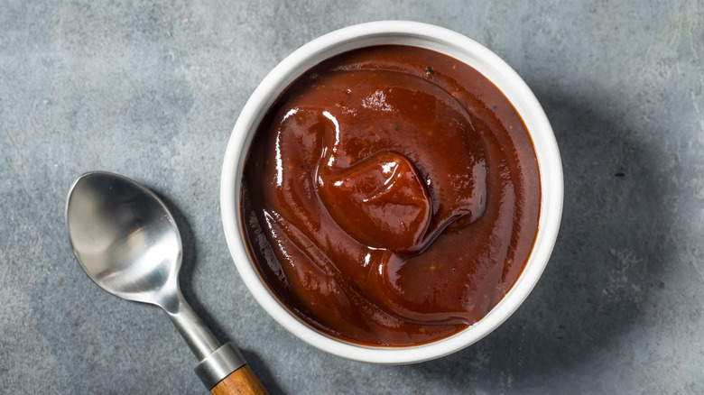 A bowl of homemade barbecue sauce next to a spoon.