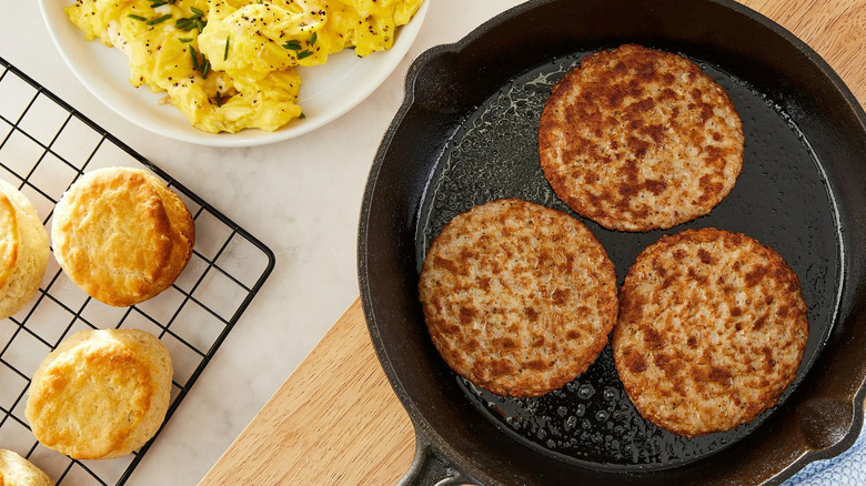 Great Value's Cooked Pork Sausage Patties in a pan surrounded by eggs and biscuits