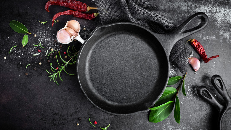 Cast iron pan with spices on black background