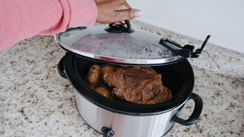 Steak braising in crock pot on a counter