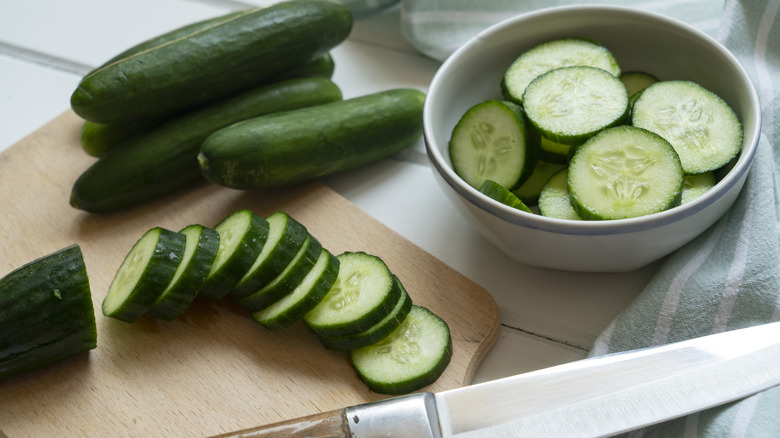 Cucumber slices on wooden cutting board next to knife