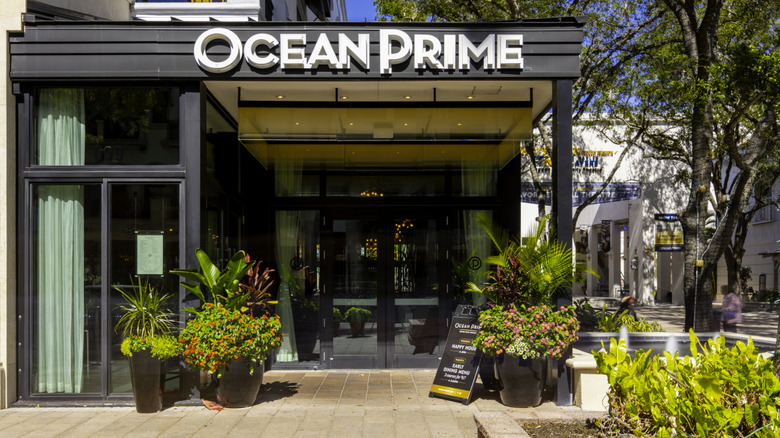 exterior of ocean prime restaurant with plants and a sign outside