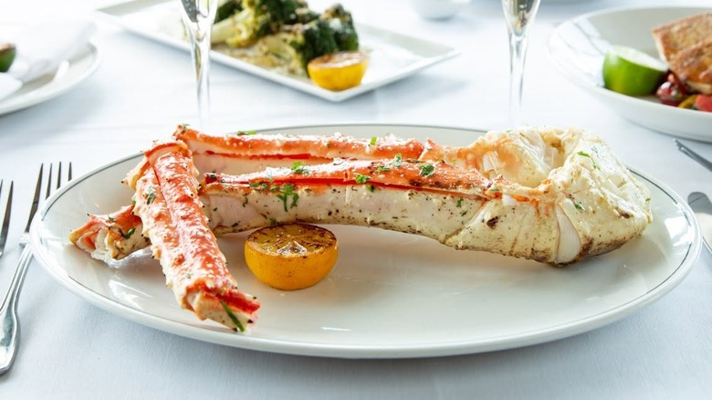 several king crab legs on a plate with a lemon on a dining table