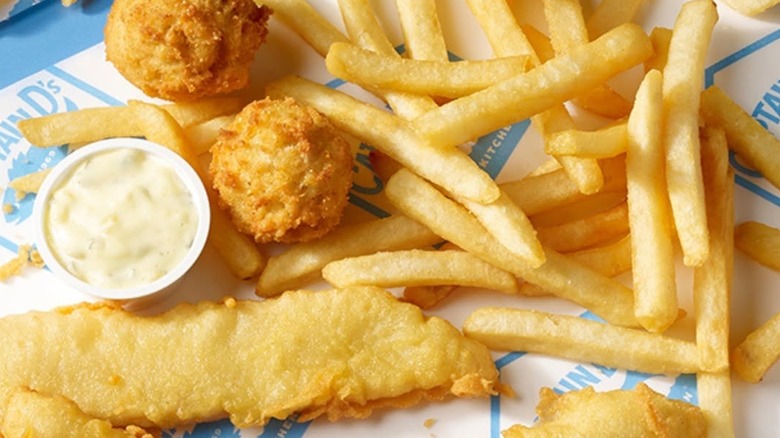 close up of fried fish and fries with sauce on top of captain d's paper