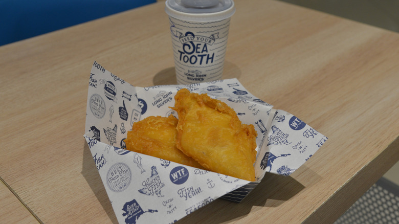 Long John Silver's fried fish in a paper dish with a to go cup on top of a table